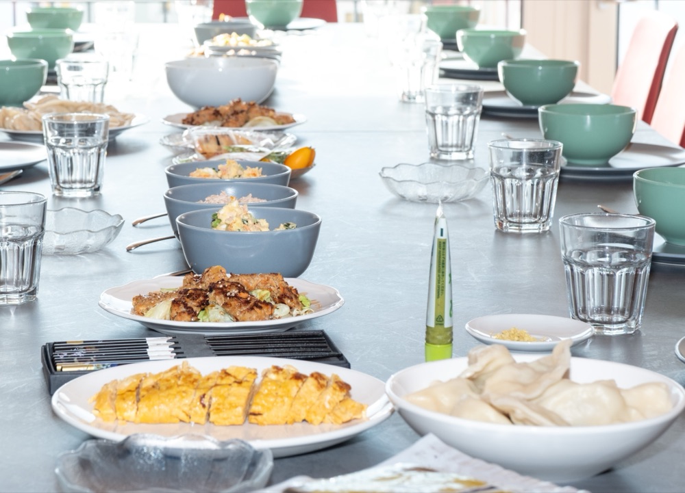Long table set for the team with bowls, dumplings and shared plates of the finished dishes
