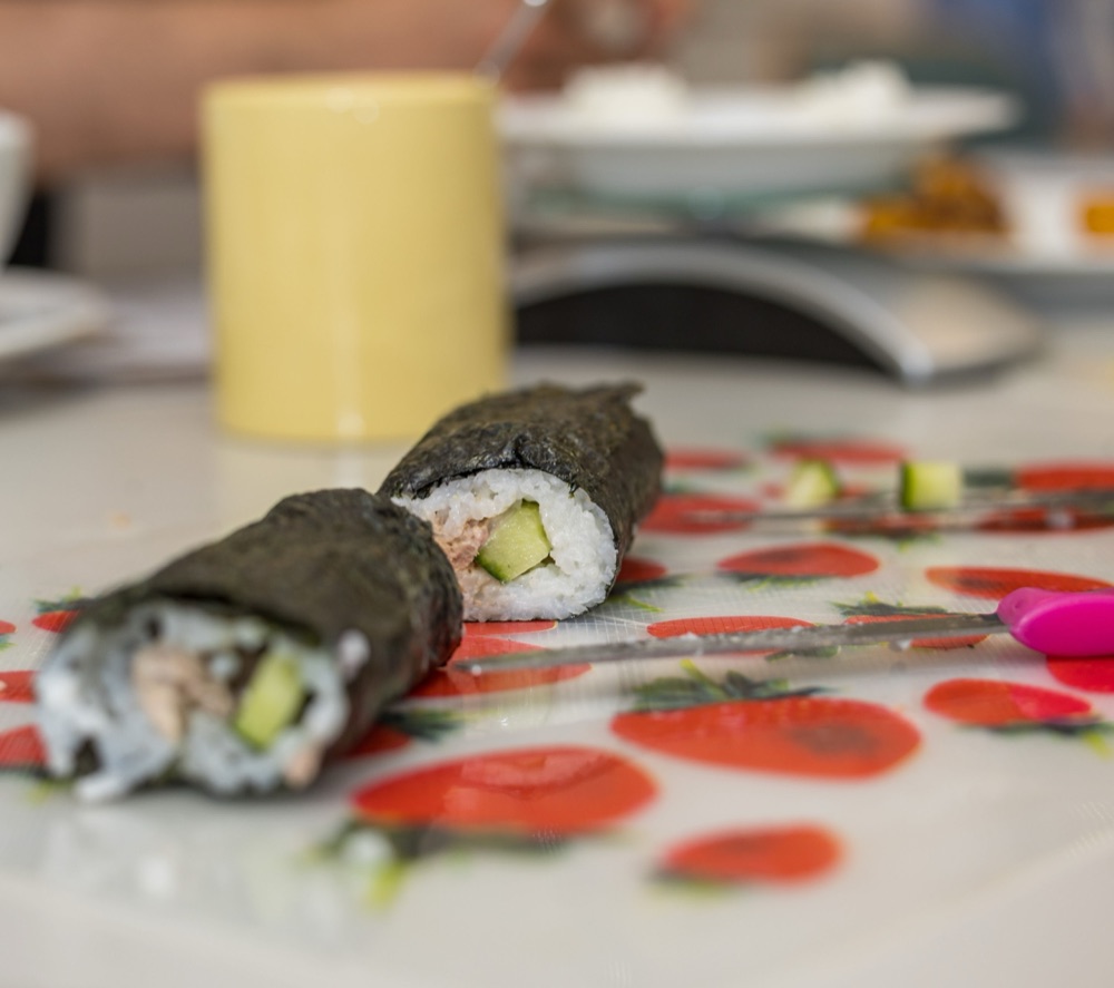 Two hand-rolled maki pieces with cucumber and tuna on a floral cutting mat